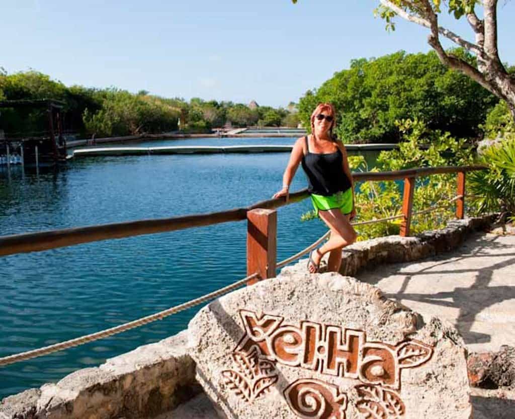 Sarah standing behind a rock Xel Ha sign at the water park in Riviera Maya Mexico